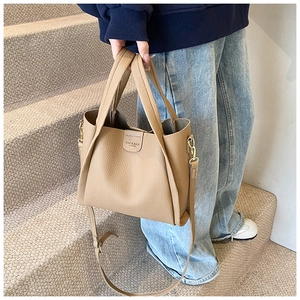 Macro shot of khaki lychee grain leather bucket bag with adjustable strap and buckle