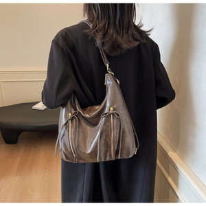 Detail of retro dark brown tote bag showing worn PU leather texture and zip accents