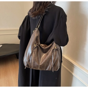 Detail of a brown oversized hobo bag featuring retro texture and leather tassels