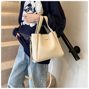 Detail view of cream white pebble leather tote bag featuring sturdy handles and shoulder strap