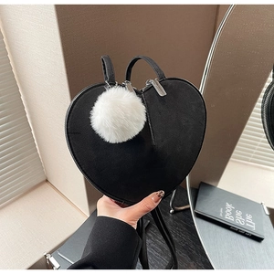 Détail d'un sac à main noir en daim en forme de cœur avec un pompon duveteux