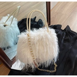 Detail of white fluffy faux fur handbag with elegant pearl strap and gold chain