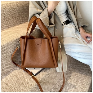 Close-up of brown litchi pattern leather tote bag with gold metal buckle detail