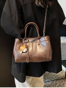 Sac à main vintage marron avec fermoir métallique et détail de charme baseball