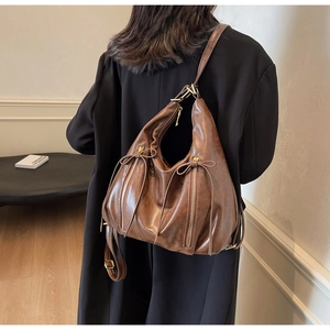 Detail view of large vintage brown leather backpack worn with a black blazer for work