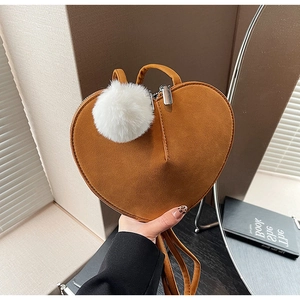 Détail du sac à bandoulière en daim en forme de cœur avec pompon en peluche et fermeture