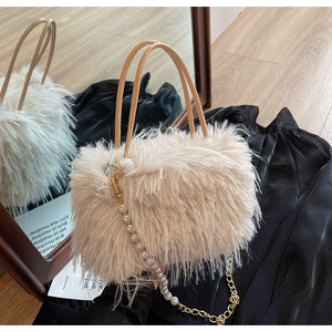 Detail of beige faux fur bucket bag featuring pearl metal chain and plush texture