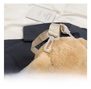 Close-up of durable white plastic hook and beige nylon strap on plush poodle bag