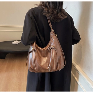 Detailed view of a vintage brown leather tote bag with stylish bows and vertical zippers