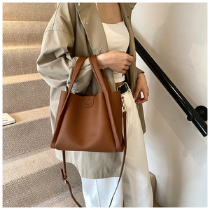 Brown litchi grain leather bucket bag shown in a stylish urban lifestyle setting