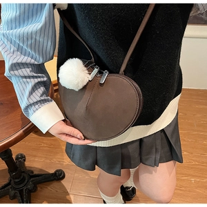 Détail d'un sac à bandoulière en forme de cœur marron foncé avec pompon en fausse fourrure