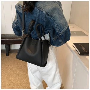 Detail view of black lychee grain leather bucket bag with top handles on a model