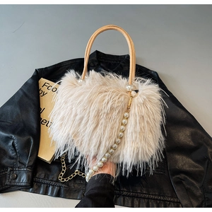 Close-up of cream faux fur bucket bag with pearl strap on black leather jacket