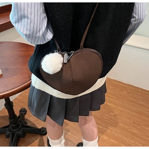 Détail du sac cœur en daim marron foncé avec un charmant pompon blanc moelleux