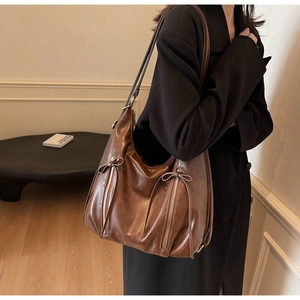 Brown vintage hobo bag with zipper details and bow drawstring shown on model side view