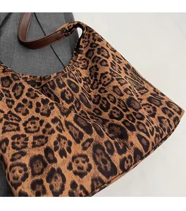 Détail rapproché du tissu d'un sac cabas léopard avec bandoulière en cuir marron