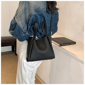 Detail of black pebbled leather tote bag showing crossbody strap and gold metal hardware