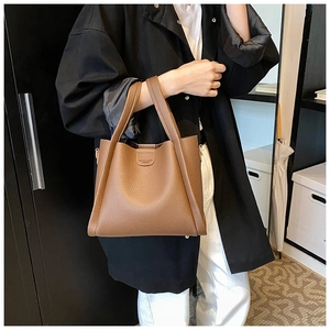 Close-up of brown litchi grain leather tote bag with embossed logo on the front panel