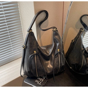 Macro shot of black hobo bag details showing dual metal zippers and leather bow ties
