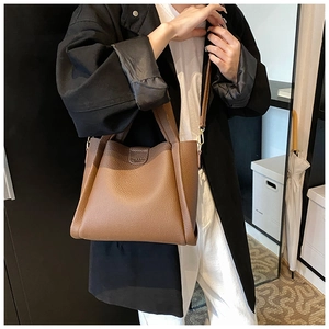 Close-up of brown lychee grain leather bucket bag featuring a fine detachable shoulder strap