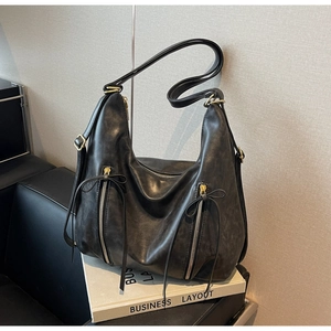 Detail of black large capacity shoulder bag with distressed leather texture and long tassels