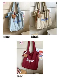 Detailed view of canvas tote bags in blue, khaki, and red with bear charm