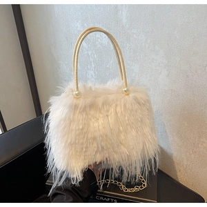 Detail of white faux fur bucket bag featuring pearl accents and gold metal handles