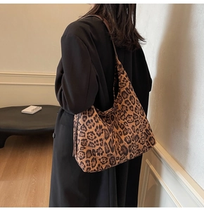 Détail d'un grand sac cabas léopard porté avec un long manteau d'hiver noir élégant