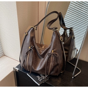 Close-up of deep brown hobo bag featuring bow-tie zipper details and matte leather texture