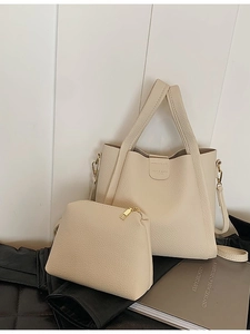 Creamy white pebble leather tote bag set with matching pouch on a black surface