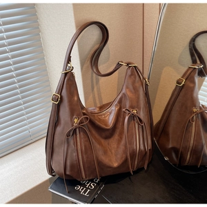 Detail of dark brown Hobo bag featuring vertical zippers, leather bows, and gold hardware