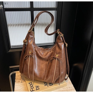 Detail of brown vintage hobo bag with zip pockets and bow accent on books