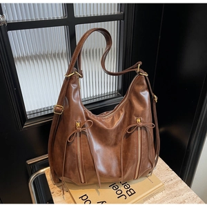 Detail view of large brown hobo bag with tassel zippers on a decorative book