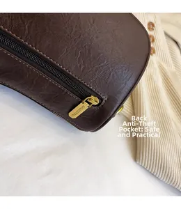 Detail of dark brown leather bag with functional back zipper pocket and golden hardware