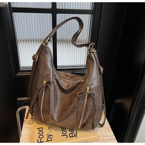 Detail of dark brown faux leather hobo bag with bow drawstring and vertical zippers