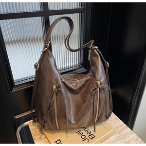 Detail of dark brown leather tote with decorative tassel zippers and gold hardware