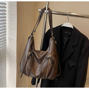 Detailed view of brown leather hobo bag featuring vertical zippers and tassel accents