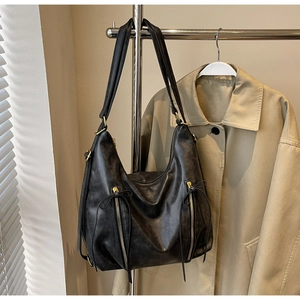 Detail of black vintage hobo bag featuring decorative gold zippers and chic leather bow ties