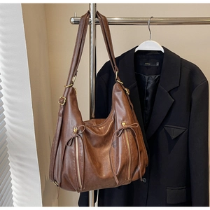Detail of vintage brown leather hobo bag with gold zippers and decorative drawstrings