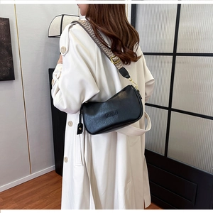 Detailed side view of black leather pillow bag with stylish wide houndstooth shoulder strap