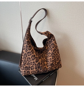 Détail d'un sac hobo vintage à imprimé léopard avec bandoulière en cuir sur un livre