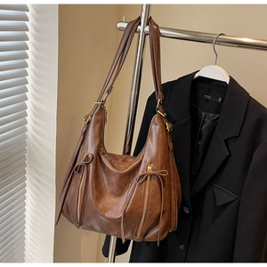 Detailed texture of brown faux leather hobo bag with decorative zippers and bow accents