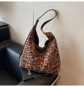 Détail du sac hobo à motif léopard avec bandoulière en cuir marron sur canapé noir