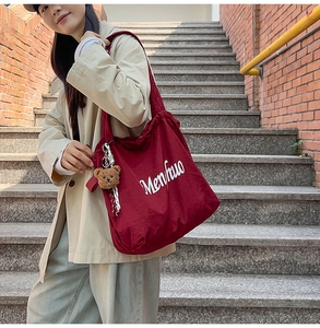 Burgundy drawstring tote bag with Menhuo text and cute brown bear plush charm detail