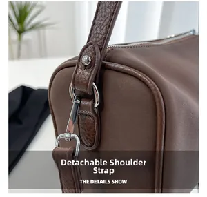 Détail de la bandoulière amovible sur un sac polochon marron avec des finitions argentées