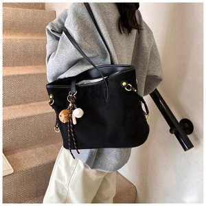 Détail du grand sac cabas noir en daim avec anneaux dorés et breloque de baseball