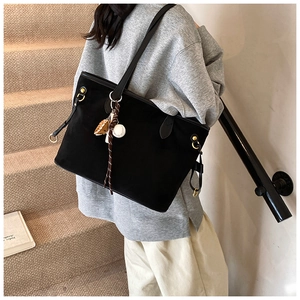 Détail du sac cabas en daim noir avec boucle métallique et breloque gant de baseball