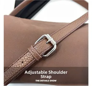 Détail de la bandoulière réglable en cuir avec boucle en métal argenté sur un sac marron