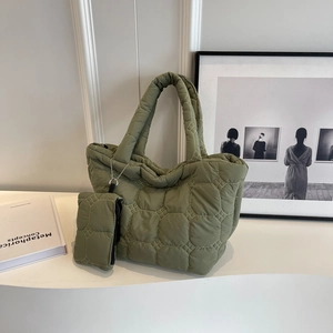 Detailed view of green quilted puffer tote bag with matching zipper pouch on white stand