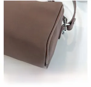Détail du sac en cuir marron montrant les coutures fines et la boucle en métal argenté